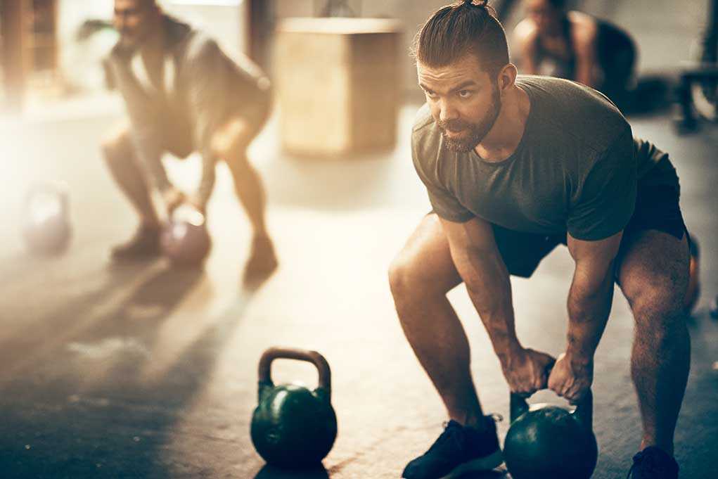 Man lifting kettlebell in a gym setting