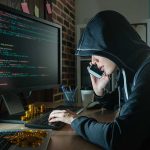 Is Your Old Android Phone a Hotbed for Cyber Threats? Hacker in hood using computer and phone analyzing code
