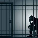 Silhouette of person sitting in a jail cell
