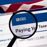 Magnifying glass over IRS website paying taxes
