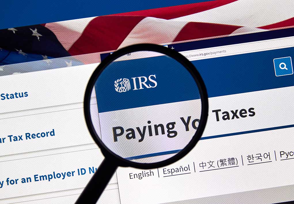 Magnifying glass over IRS website paying taxes