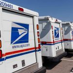 Row of USPS mail trucks parked in lot