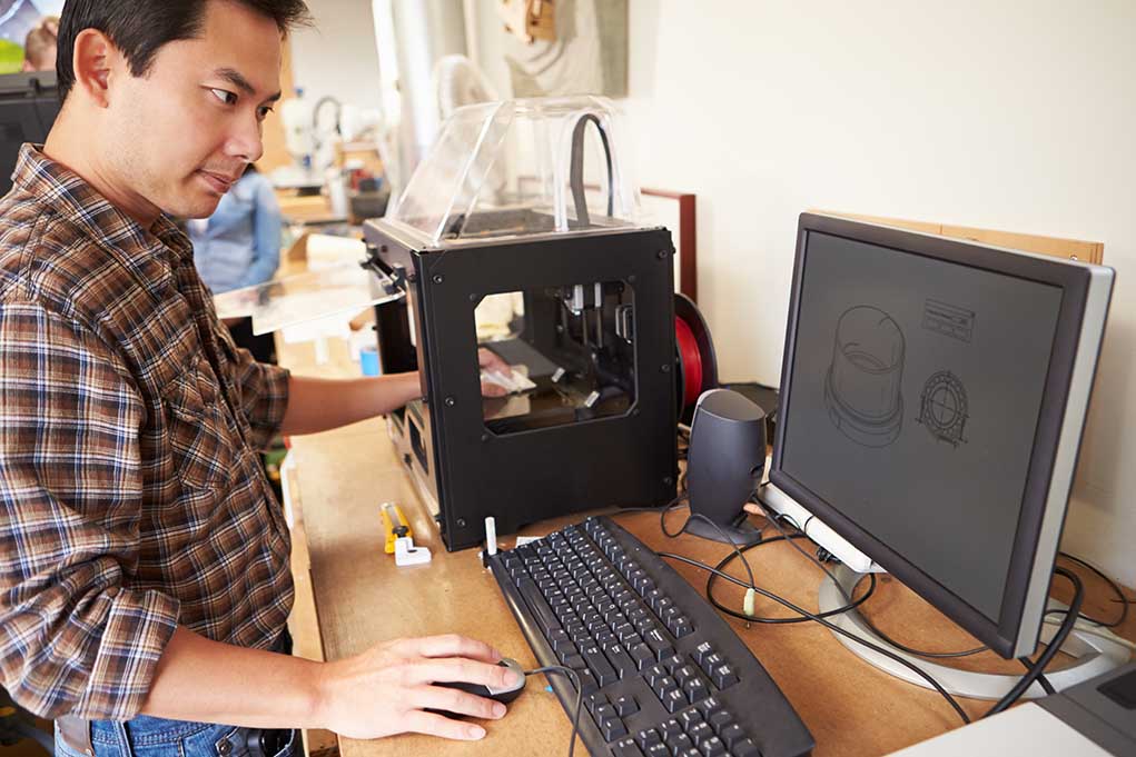 184664579 featured image Man operating 3D printer and computer workstation