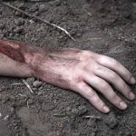 Injured arm partially buried in dirt