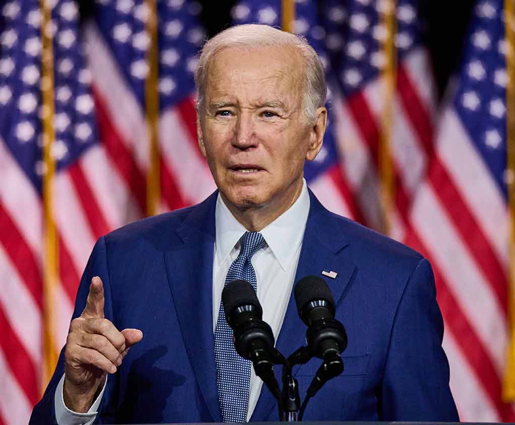 Man speaking at podium with American flags behind