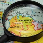 Magnifying glass over a map of Venezuela.