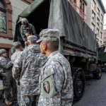 Soldiers gather around a military truck on street