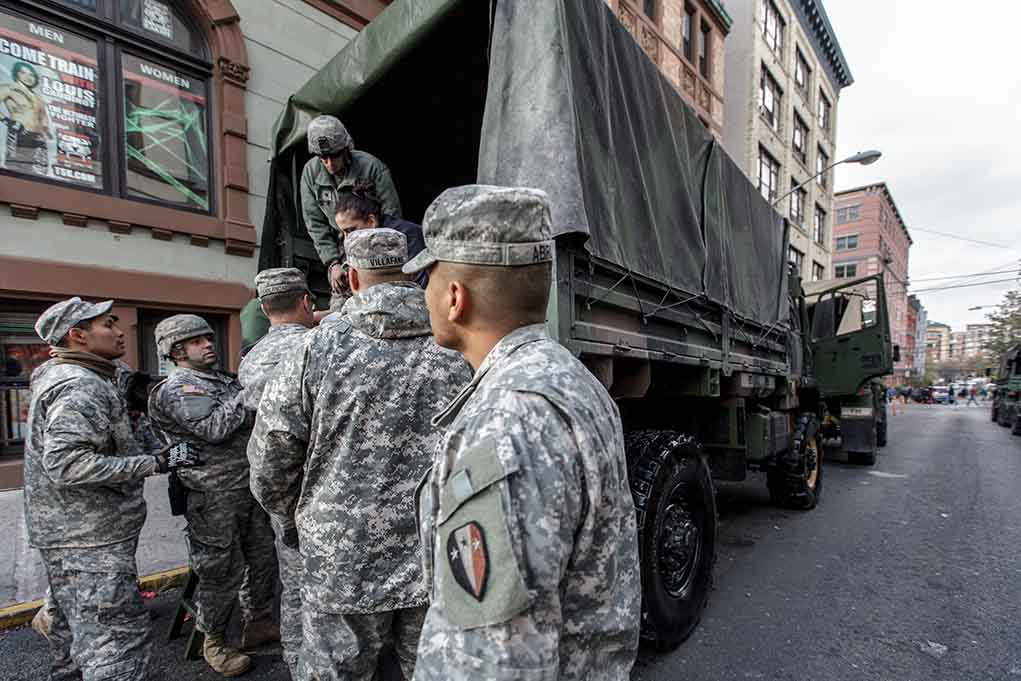 Soldiers gather around a military truck on street