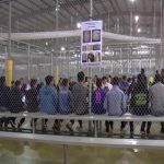 People sitting on benches inside a fenced facility
