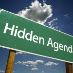 Green road sign reading Hidden Agenda sky background