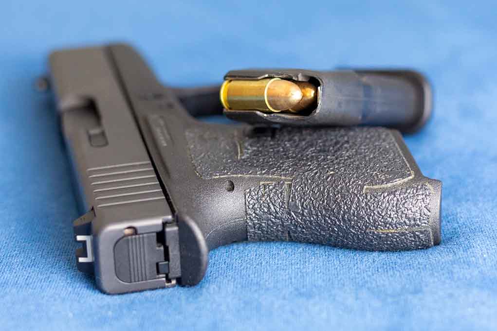 2159542825 featured image Handgun on blue fabric with visible bullet cartridge