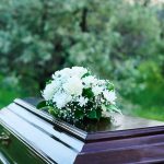 Coffin with white flowers outdoors in green surroundings