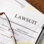 Trump DOJ Slams State Over Illegal Benefits Lawsuit papers with glasses and pen on table