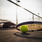 Tennis racket and ball on court near net