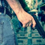 Person holding a gun in a crowded street
