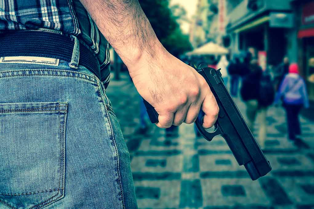 Person holding a gun in a crowded street