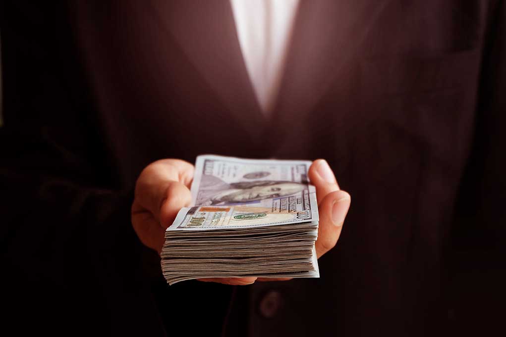 71912373 featured image Hand holding a stack of hundred dollar bills