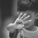 Child holding up hand with STOP written on palm