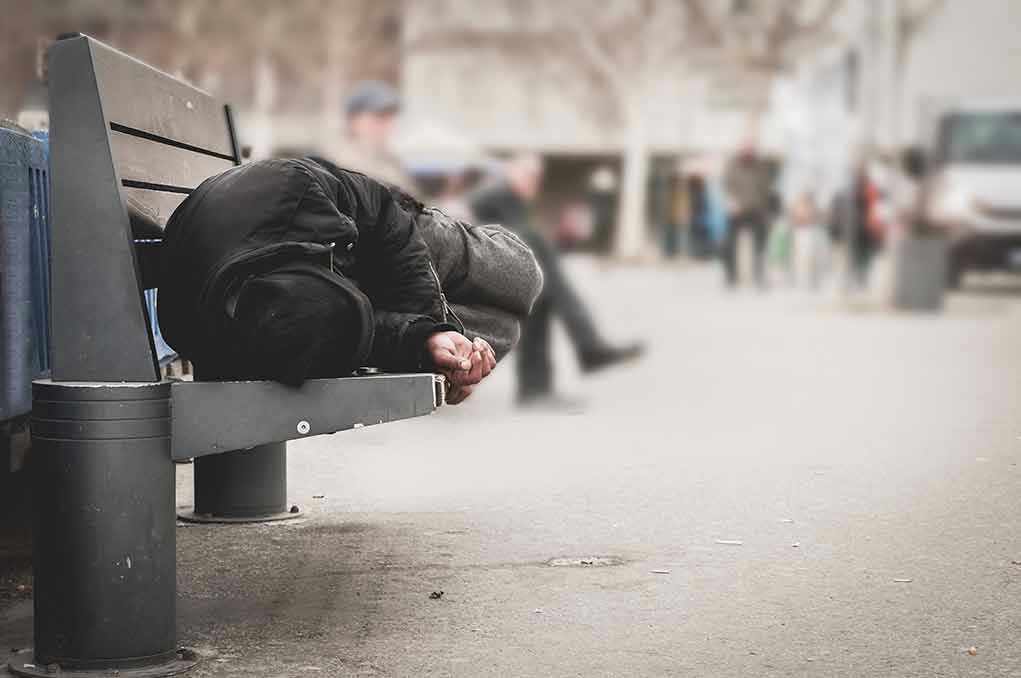 1016111287 Person sleeping on a bench in a public area