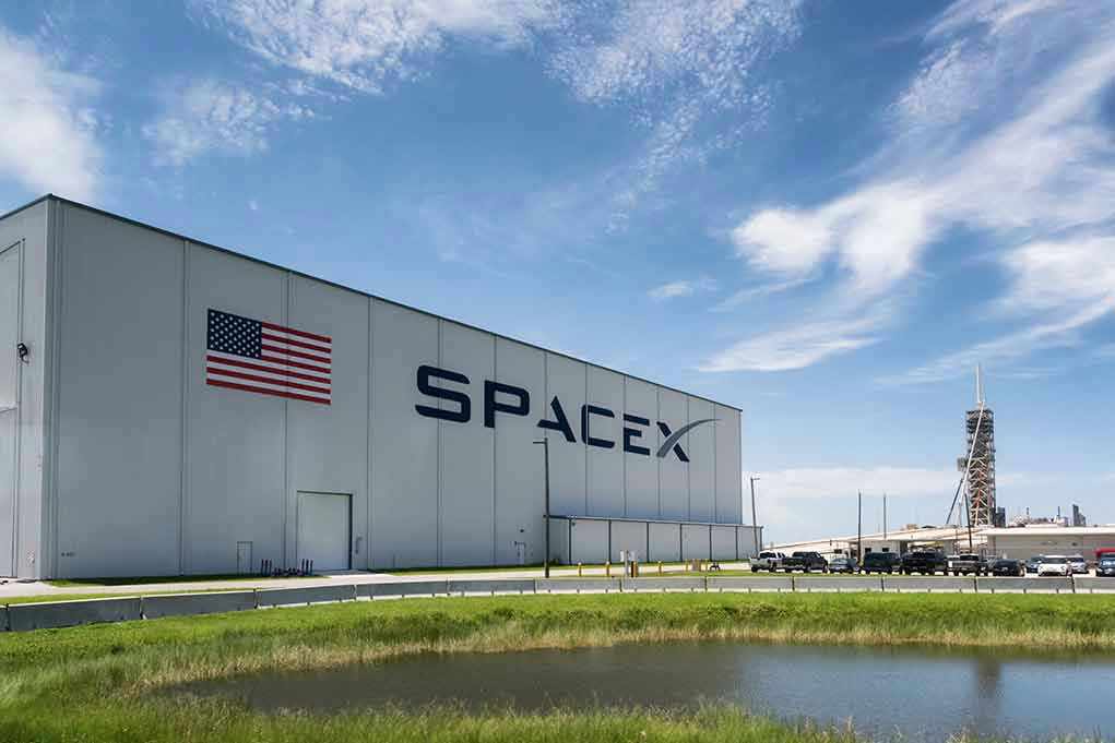 1113361880 SpaceX building with American flag and launch pad