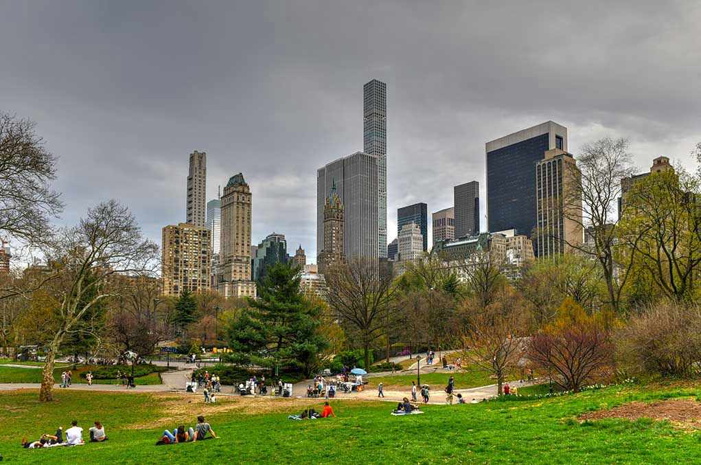 1382597744 People relaxing in a park, city skyline background