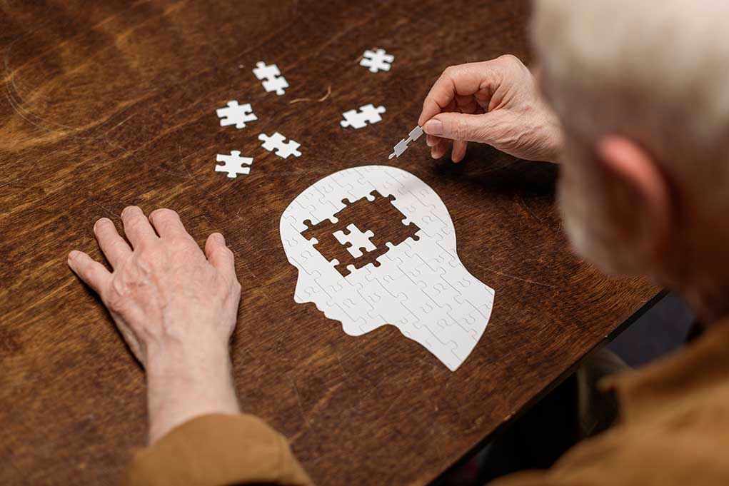 Elderly person completing head-shaped jigsaw puzzle