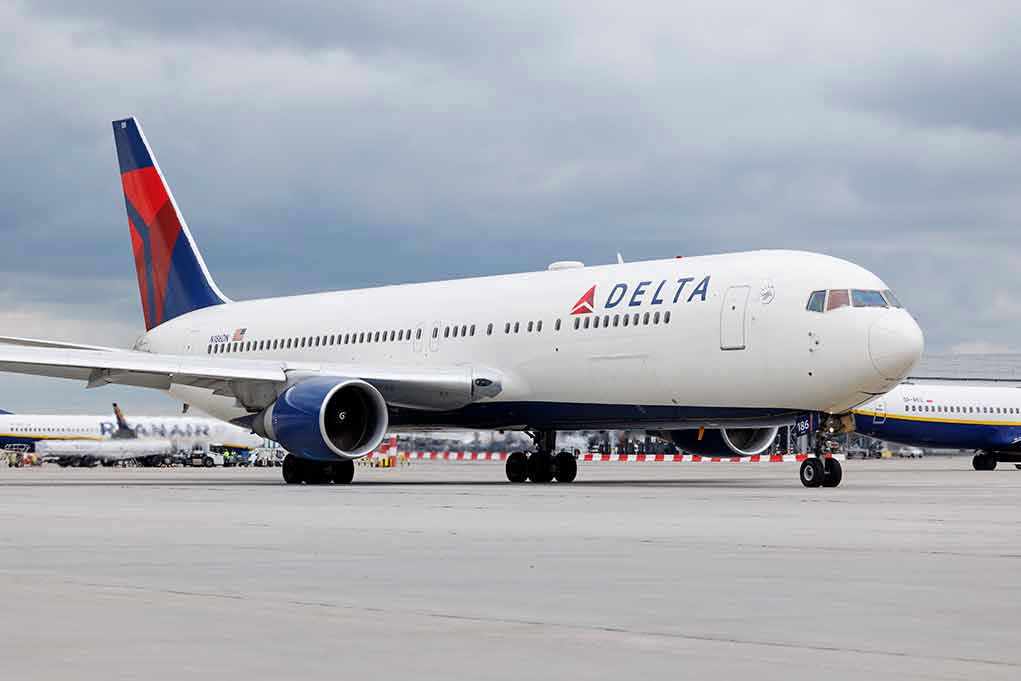 Delta Airlines airplane on airport runway, cloudy sky