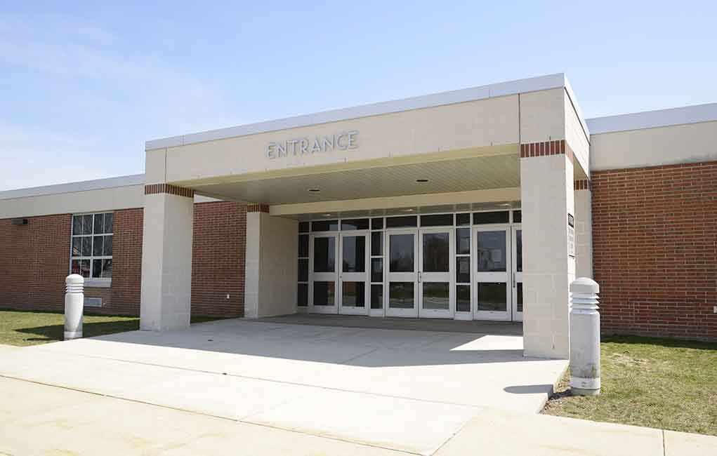 Entrance of a modern school building with glass doors and a brick facade