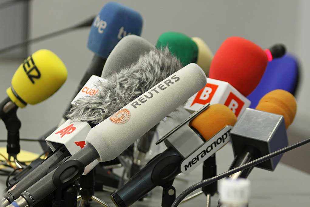 A collection of various microphones arranged for a press conference