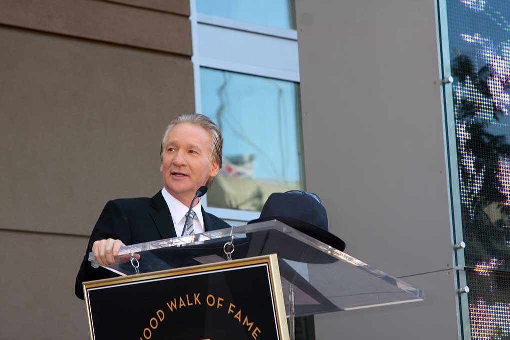 A man in formal attire speaking at a podium during a Hollywood Walk of Fame ceremony