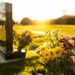 Sunlit cemetery with flowers on headstone