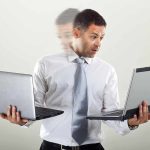 Man holding two laptops and looking surprised