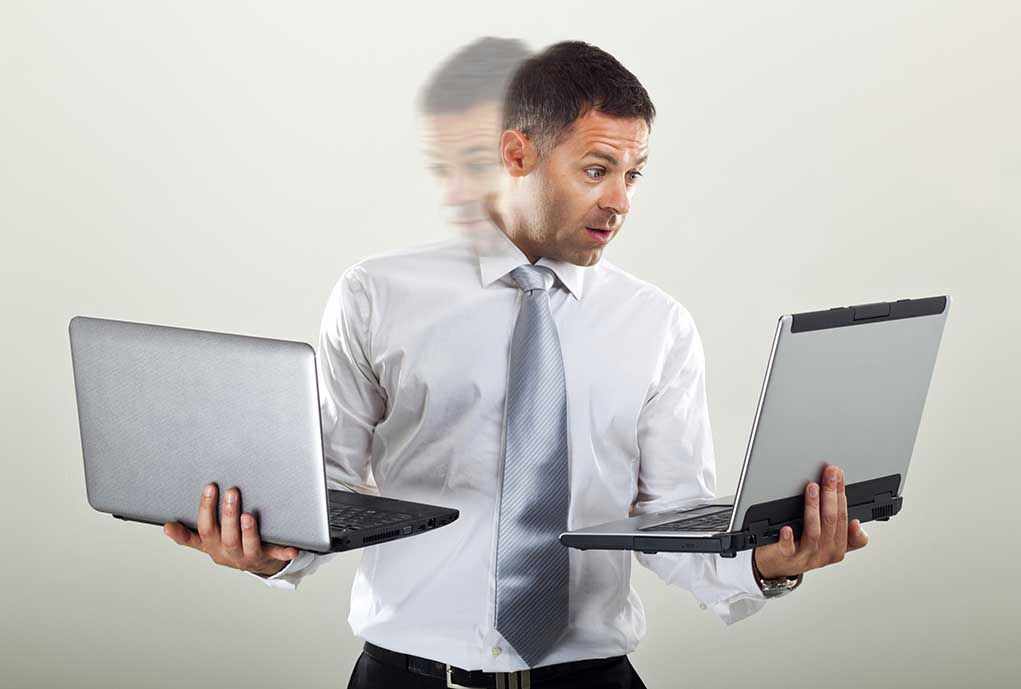 Man holding two laptops and looking surprised