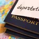 Stack of passports with a note labeled 'deportation' on top, placed on a map