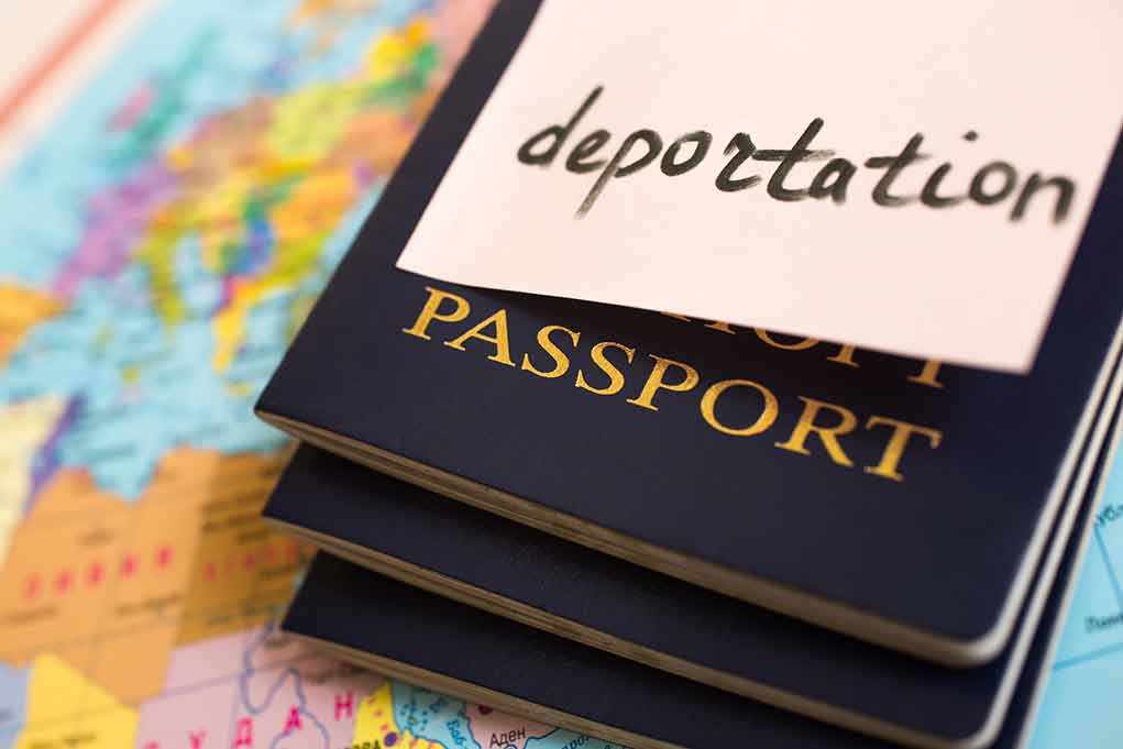 shutterstock_279449597.jpg Stack of passports with a note labeled 'deportation' on top, placed on a map