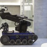 A robotic arm mounted on a tracked base in a modern workspace