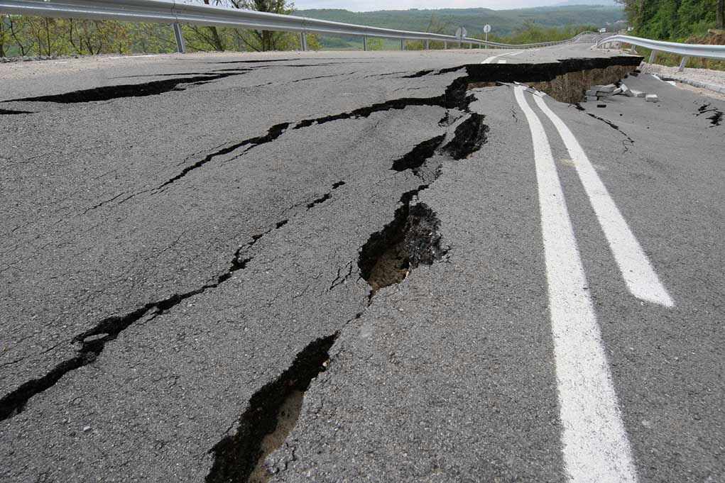 1044748162 Road damaged by significant cracks and fissures.