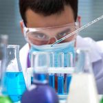 Baldness Breakthrough – End of Hair Loss? Scientist pipetting blue liquid into test tubes.