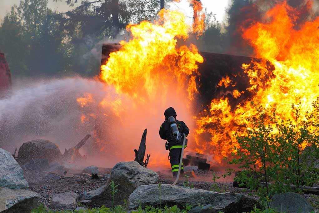 shutterstock_109414631.jpg Firefighter battling a large fire with water spray