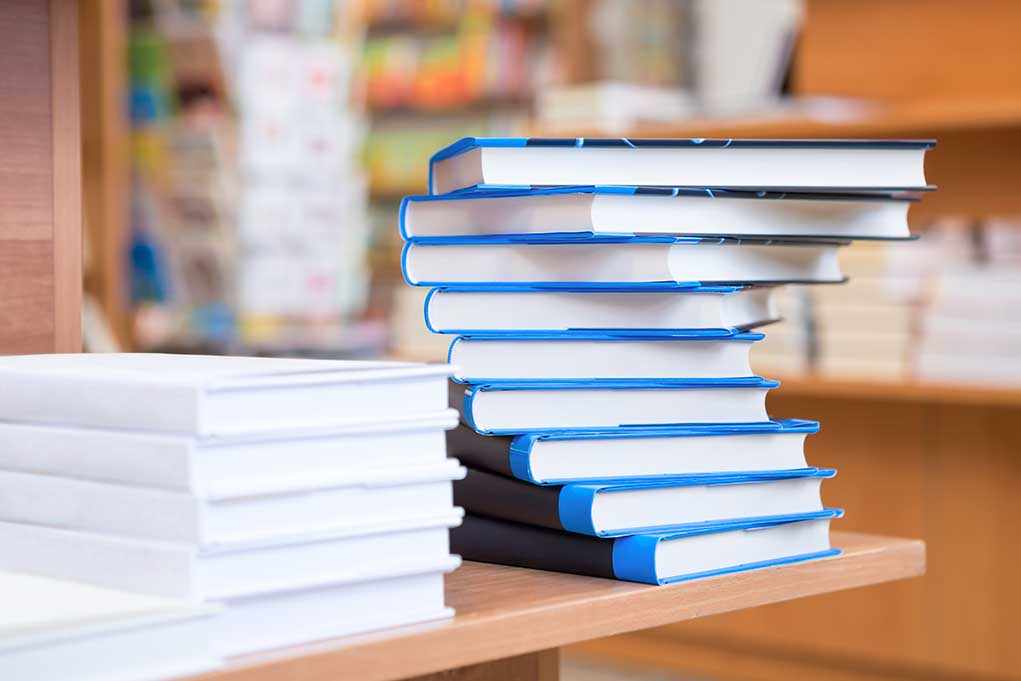 A stack of neatly arranged books on a wooden table in a bookstore