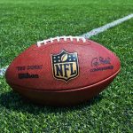 NFL Mourns Shocking Death — What Really Happened NFL football on a green field.