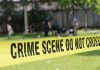 Couple ARRESTED After HORRIFYING Backyard Discovery Yellow crime scene tape blocking grassy area.