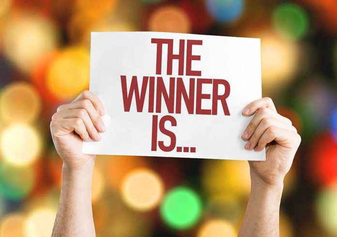 322328513 Hands holding a sign reading The Winner Is...