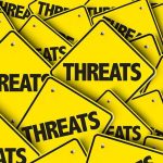 Threats Force “Dr. Antifa” Into Hiding Yellow warning signs with the word THREATS.