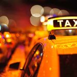 Armed Driver CRASHES Consulate — Diplomatic Chaos Close-up of a taxi sign illuminated at night with blurred city lights in the background