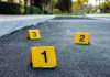 Crime scene markers on asphalt with bullet casing.