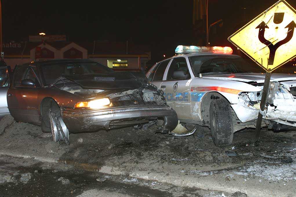 A damaged car and a police vehicle involved in a nighttime accident