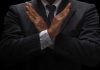 A man in a suit crossing his arms in a gesture of refusal or rejection