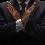 Governor’s Shocking Move — AI Bill Protecting Kids Blocked A man in a suit crossing his arms in a gesture of refusal or rejection