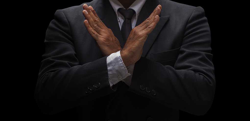 A man in a suit crossing his arms in a gesture of refusal or rejection